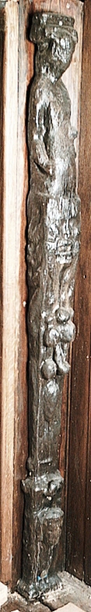 Skulpterad pilaster utformad som en karyatid med långt hår, troligen placerad under ett joniskt kapitäl.
Huvudet är vridet åt vänster. Höger arm är sträckt utefter sidan. Vänster arm är böjd och i handen håller figuren ett okänt föremål.
Pilasterskaftet är upptill prytt med en maskaron med bred, öppen mun och nedtill med en tung fruktfeston. Det nedåt avsmalnande pilasterskaftet avgränsas från piedestalen av en enkel vulst eller list med uppdragna kanter. Piedestalen är hög och jämnbred samt prydd med ett litet huvud och avslutas nedtill med en förtjockad bas. Skulpturens baksida är slät.
Skulpturen är kraftigt sliten och nött med finare detaljer utplånade.

Text in English: Sculpted pilaster with Caryatid with long hair under what is possibly an Ionic capital.
The head is turned to the left, the right arm is streched along the side, the left arm is bent and the hand holds an unknown object.
The shaft of the pilaster is decorated above with a mask with a broad, open mouth, below is a heavy festoon of fruit. The shaft tapers downwards and is divided from its pedestal by a simple torus or batten with drawn-up edges. The pedestal is high and even in width and decorated with a small head. It terminates at the bottom in a thickened base. Its back is smooth.
The sculpture is much worn, with finer details obliterated.