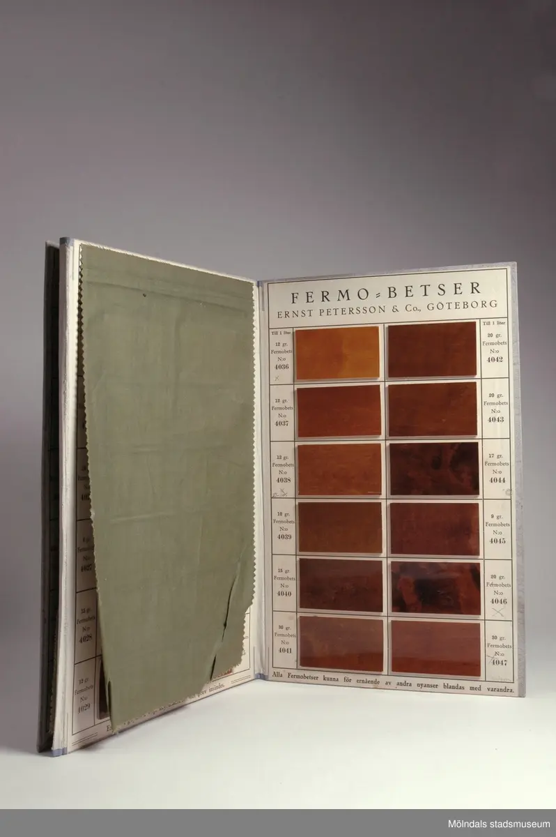 Provkarta med möbelträbetsfärger.Redskap och verktyg kommer från Lindströms snickeri (Gamla Riksvägen 81, Ekebacken). Här byggde John Lindström från Lindome ett boningshus och snickeriverkstad 1928. Han öppnade ett snickeri som specialiserade sig på köksbord Borden levererades till en grossist i Göteborg. Som mest tillverkades 50-60 bord i veckan. Borden hade ben av björk och resten var av furu. Han gjorde även andra möbler på beställning. Till hjälp hade John ett par anställda.De sista åren gjordes mest renoveringar och reparationer, medan det "begav sig" de mest aktiva åren tillverkades bord av alla de slag.