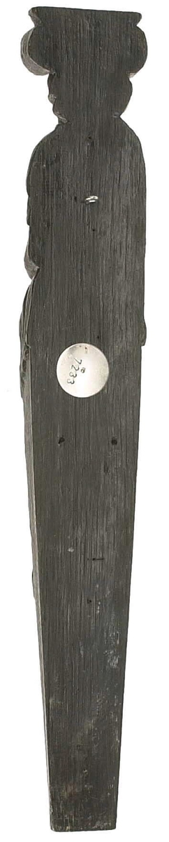 Hermpilaster.
Liten skulpterad pilaster föreställande skäggig herm under joniskt kapitäl.
Huvudet är vridet mot vänster. Hermen är insvept i en mantel som hålls fast med vänster hand framför magen. I höger hand håller figuren ett okänt föremål (blomsterkälk?) framför bröstet. Pilasterskaftet är prytt med stora frukter och blad, fasthängande vid en stängel som delvis täcker det nedåt avsmalnande skaftets ramverk. Baksidan är slät.
Skulpturen är mycket välbevarad med sju spikhål.

Text in English: Small sculpted pilaster with a bearded Herm beneath an Ionic capital.
The head of the figure is turned to the left. The Herm is enveloped in a mantle, held fast with the left hand in front of its stomach. Its right hand holds an unknown object (a bunch of flowers?) in front of its breast. The shaft of the pilaster is decked with large fruit and leaves hanging from a stalk which partly cover the framing of the tapering shaft. Its back is flat.
The sculpture is very well preserved.