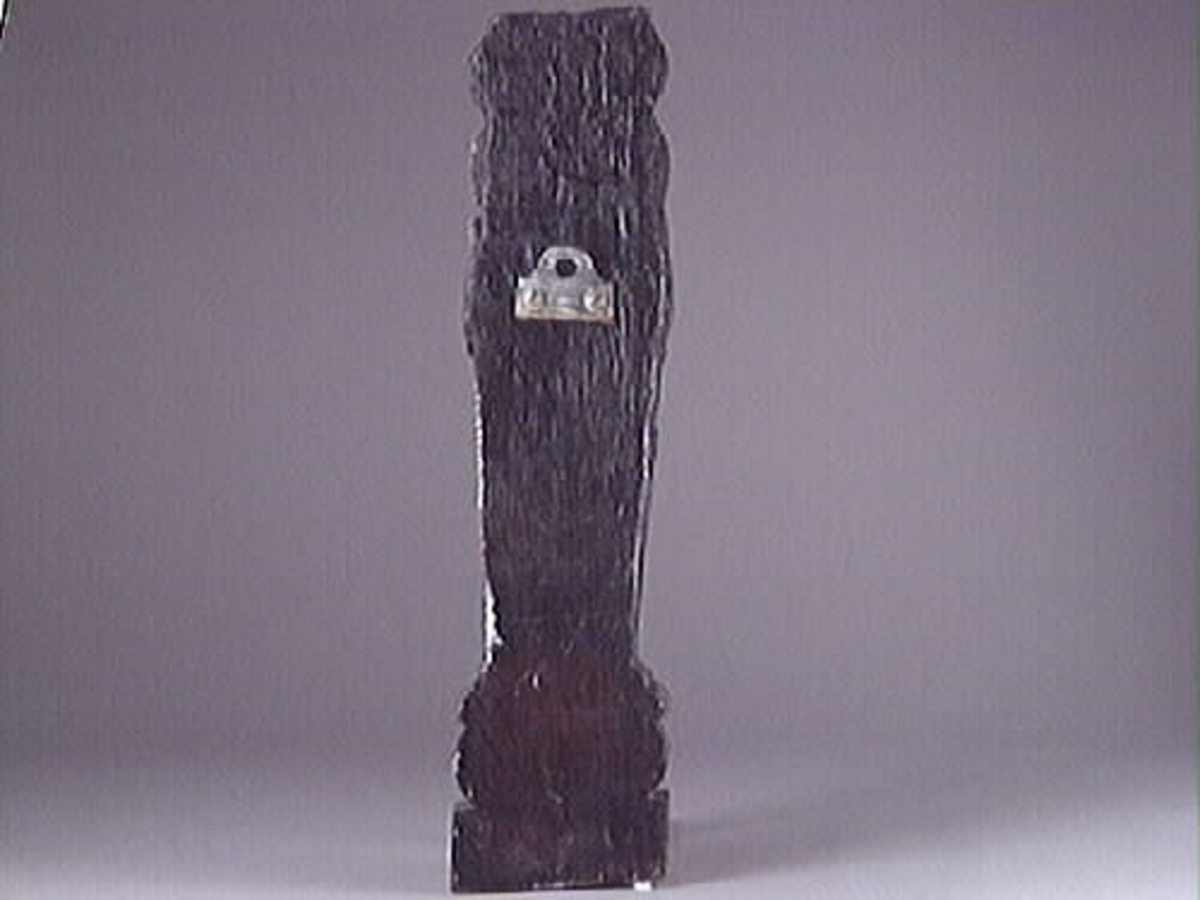 Liten skulpterad pilaster, utformad som en karyatid eller möjligen en putto. Figuren har långt hår och ett knubbigt ansikte, omgivet av en bred krage. Det nedåt avsmalnande pilasterskaftet är dekorerat med akantusblad. Nedtill avslutas pilastern av en rikt profilerad och dekorerad sockel. På skulpturens släta baksida sitter en nygjord upphängningsanordning, fästad med två skruvar.
Skulpturen är sliten.

Text in English: A small carved pilaster, with a caryatid or probably a putto. The figure has a chubby face, long hair and a broad collar. The lower part of the pilaster is decorated with acanthus leaves. The caryatid stands on a richly profiled and decorated socle. On the smooth back of the sculpture is a new hanging device attached with two screws.
The sculpture is worn.