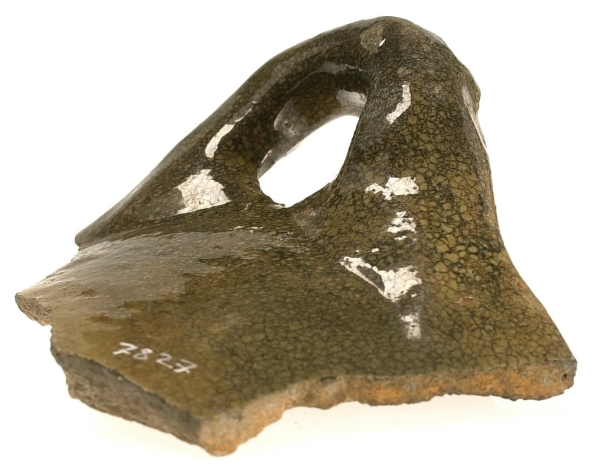 Del av skål.
1 st vertikal bandhänkel, tummad, 70 x 60 mm. Fragment av mynningsrand och buk. In- och utsida blyglaserad gulgrön.