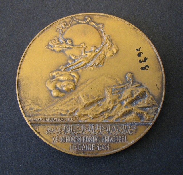 Medalj i brons, rund, präglad med anledning
avVärldspostföreningens kongress i Kairo, Egypten år 1934. På
åtsidanett porträtt i profil av Egyptens kung Fouad I, samt text
enligt MRK.Frånsidan visar en avbildning av Världspostmonumentet i
Bern, Schweiz.