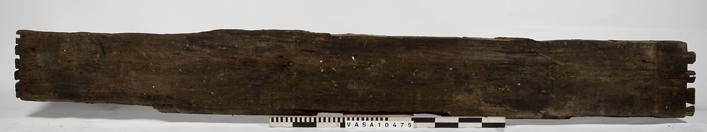 Fragment till en rektangulär bräda med väl bevarade laxstjärt stycken på ena ände. En avbruten sink på den andra ände. 2 spikhål med huvudspår längs en långkant.
det Original föremålet var dubbelt längd - avbruten längs sinket. Avbrytningar och kraftig vittring på långkanter.