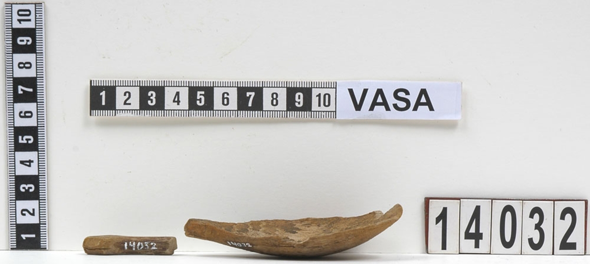 Fyra delar av en träsked. De två större delarna utgör skedskaftet samt större del av skedbladet med ett mindre parti av skaftet. De övriga två delarna utgör fragment av skedblad.

Insidan av skedbladet är dekorerad med ett ristat/glödritat vågmönster. Skedskaftet är kort och rakt, med profilerad skaftände. Längst ut på skaftänden syns en brottyta. Troligtvis har skaftet avlutats i en ändknopp. Skeden har gul-röda utfällningar samt rödbruna färgspår.

Skeddelarna är mycket ömtåliga, med sprickor.

För mer information se Dokumentationsblankett under Referenser – Länkade filer.