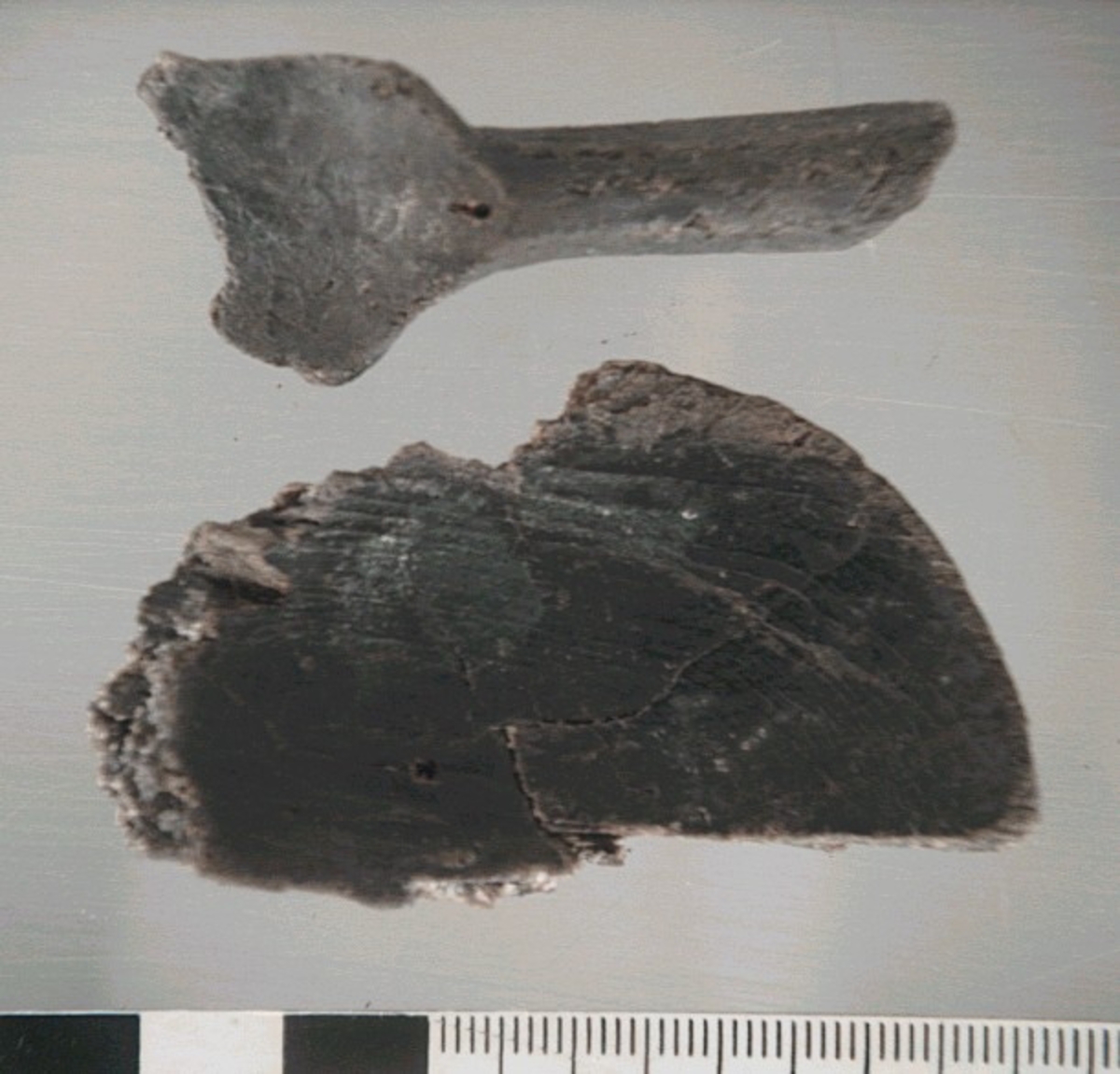 Del av skedbladet till en träsked. Skedbladet har troligtvis varit äggformat.

Skedbladet är mycket slitet, med en större spricka. Större delen av bladets ytterkanter saknas.

För mer information se Dokumentationsblankett under Referenser – Länkade filer.