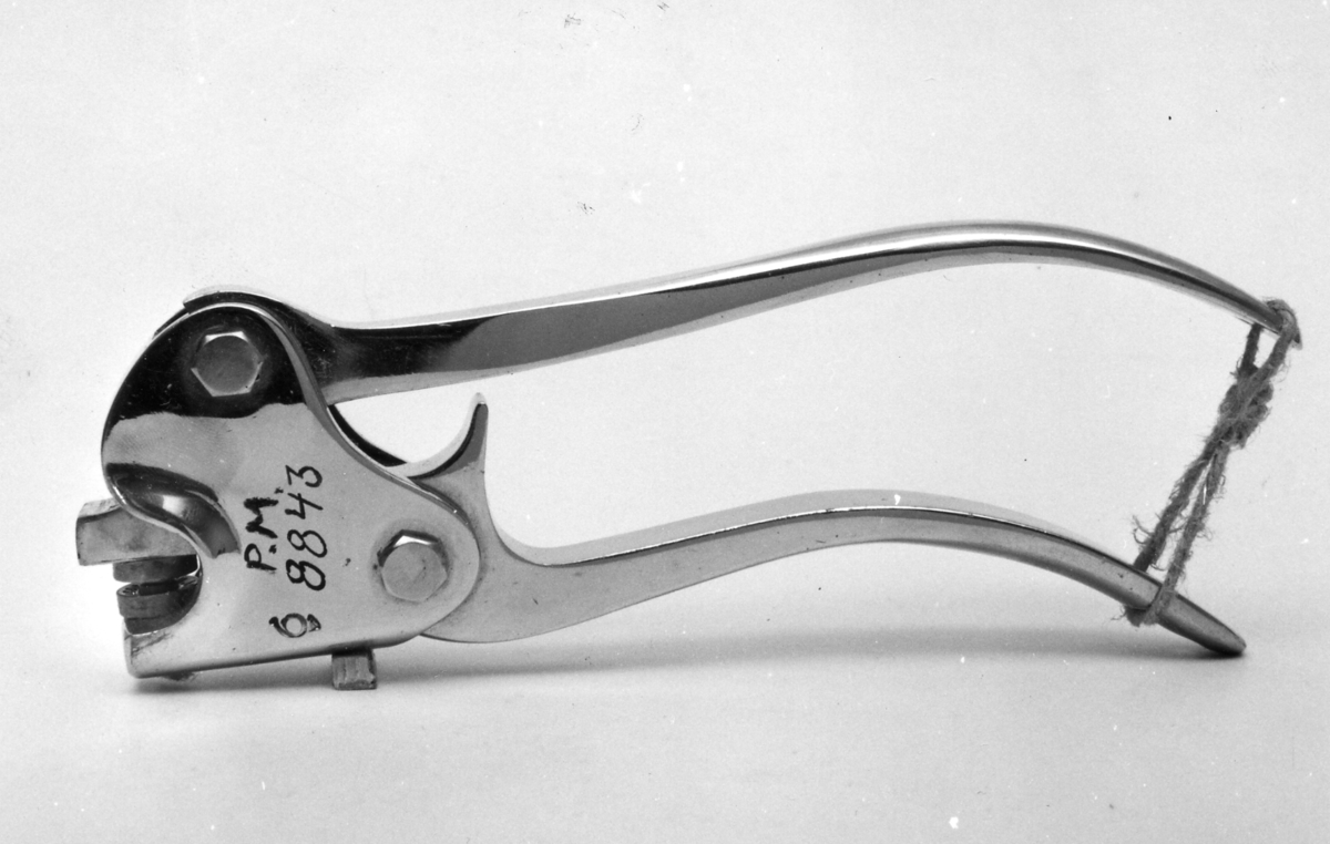 Plomberingstång av förnicklat stål med en postsymbol, posthorn och krona. I sigillet står: Sth Utst 1930.