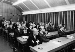 De inbjudna församlade i postskolans aula.  I första raden f