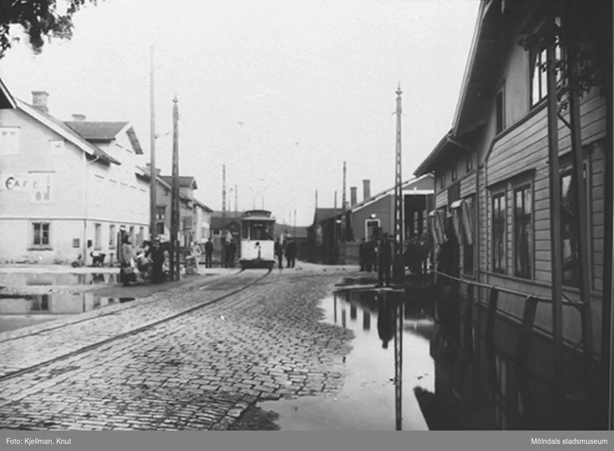 Översvämning vid Mölndalsbro, 1907, sett söderifrån från Kungsbackavägen. 4:ans spårvagn är på ingående. Från vänster: Göteborgsvägen 1, 3 och 5. På andra sidan vägen: spårvagnshallarna och Hjertstrands hus ("Bankhuset" på Kungsbackavägen 1).