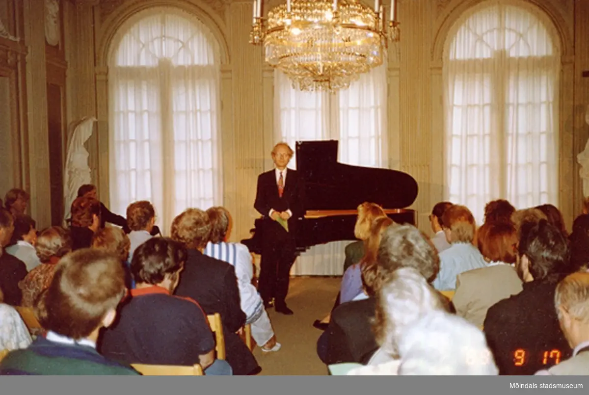 En musikkonsert inne på slottet. En man står vid ett piano.