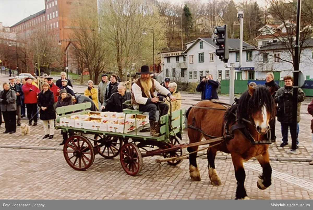 Gamla torget i Mölndal den 22:a november 2001. En hästskjuts lastad med frukt kommer till invigningen då det har varit omläggning och stenläggning av torget. I bakgrunden till höger ser man Kvarnfallet 26 (Kråkans krog).