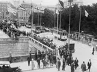 Kongresmedlemmar på väg från Riksdagshuset till Rikssalen för
kongressens högtidliga öppnande den 4 juli 1924. I spetsen
Generalpostdirektör Juhlin och ålderspresidenten de Fejer från Ungern
(marskalk Olsen). Därefter följa medlemmarna efter ländernas franska
namn i alfabetisk ordning (Albanie, Allemagne etc).