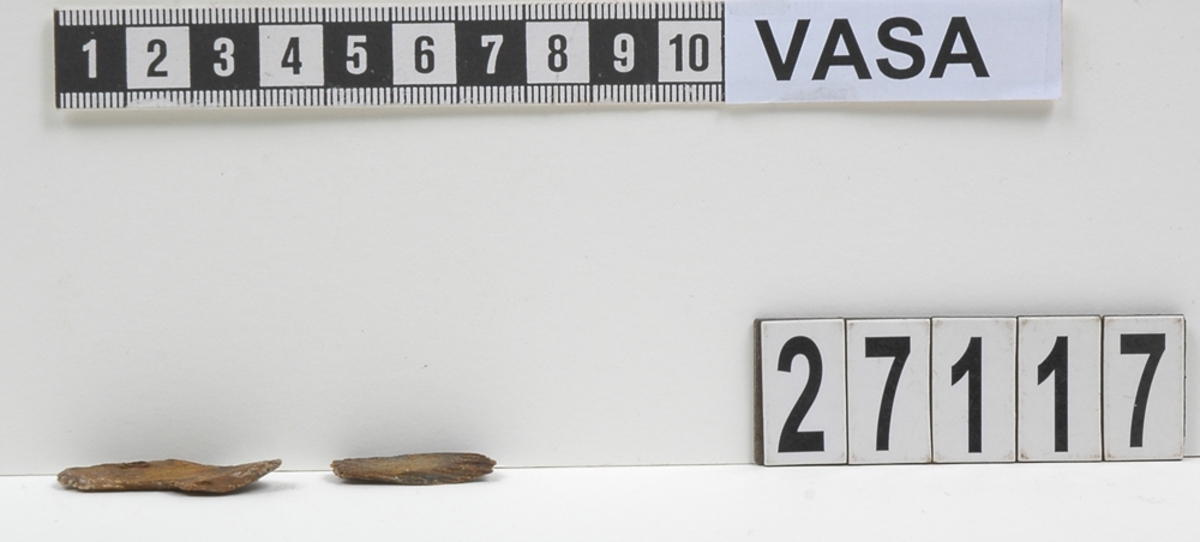 Delar av en träsked. Delarna utgör två mindre partier av skedbladet. I den ena delen syns ett litet runt hål.

Delarna är mycket slitna och fragmentariska.

För mer information se Dokumentationsblankett under Referenser – Länkade filer.