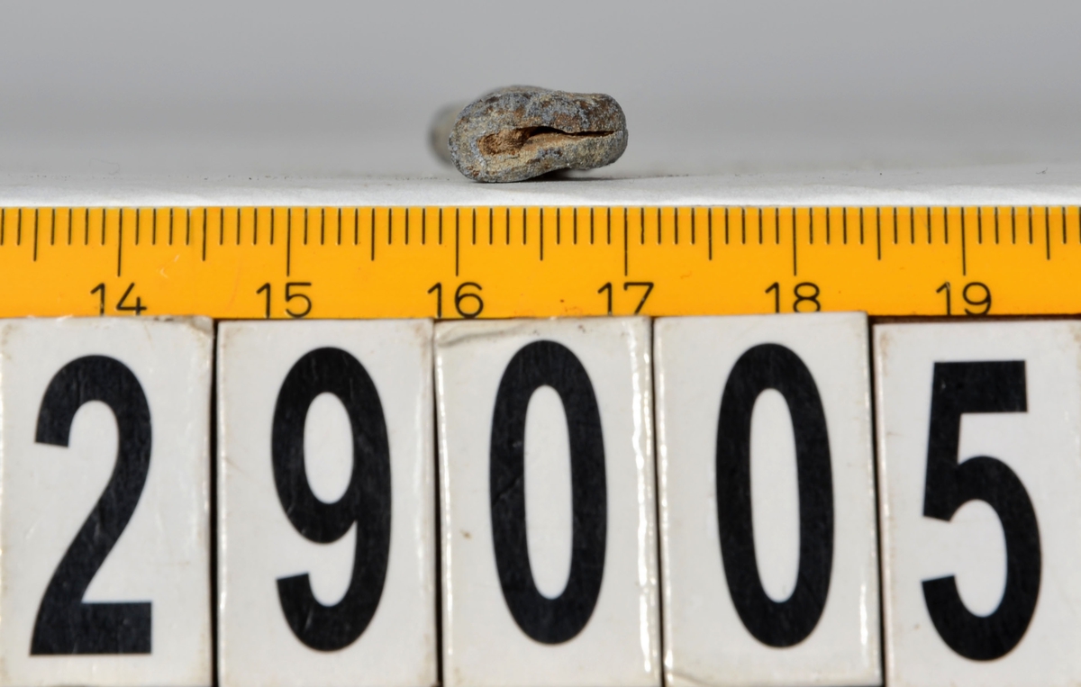 Sänket består av en vikt blybit. Sänket har tydliga märken efter det verktyg som pressat ihop sänket runt garntråden. Sänket är i gott skick.

Text in English: Lead sinker in the shape of a flat tube. The rectangular piece of lead is folded vertically in half and has visible tool marks from the folding process. The yarn is pushed through the hole. Grey mat in colour. In good condition.