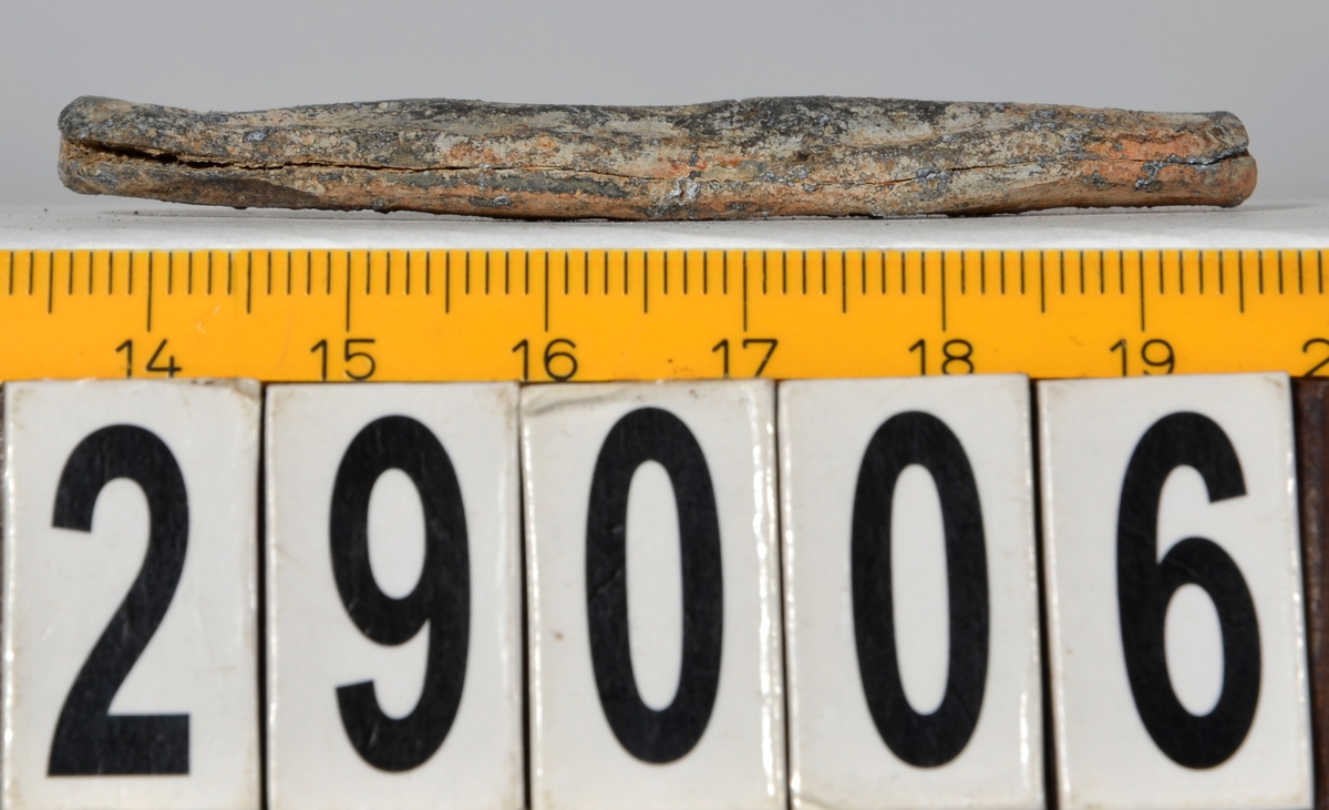 Sänket består av vikt blybit. Sänket har tydliga märken efter det verktyg som pressat ihop sänket runt garntråden. Sänket är i gott skick.

Text in English: Lead sinker in the shape of a flat tube. The rectangular piece of lead is folded vertically in half and has visible tool marks from the folding process. The yarn is pushed through the hole. Grey mat in colour. In good condition.