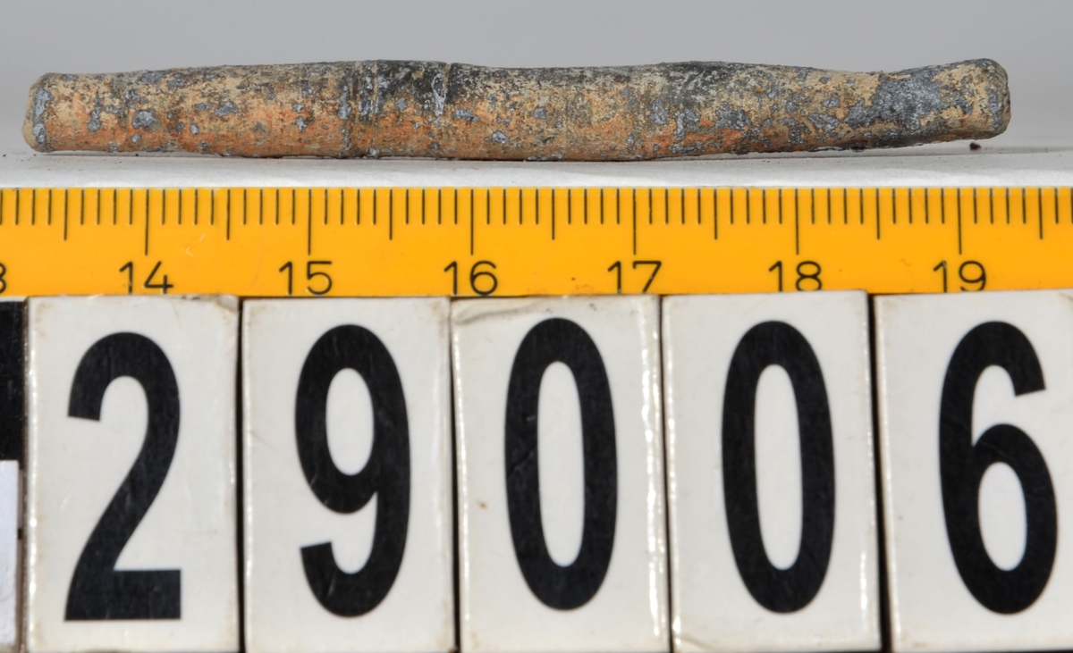 Sänket består av vikt blybit. Sänket har tydliga märken efter det verktyg som pressat ihop sänket runt garntråden. Sänket är i gott skick.

Text in English: Lead sinker in the shape of a flat tube. The rectangular piece of lead is folded vertically in half and has visible tool marks from the folding process. The yarn is pushed through the hole. Grey mat in colour. In good condition.