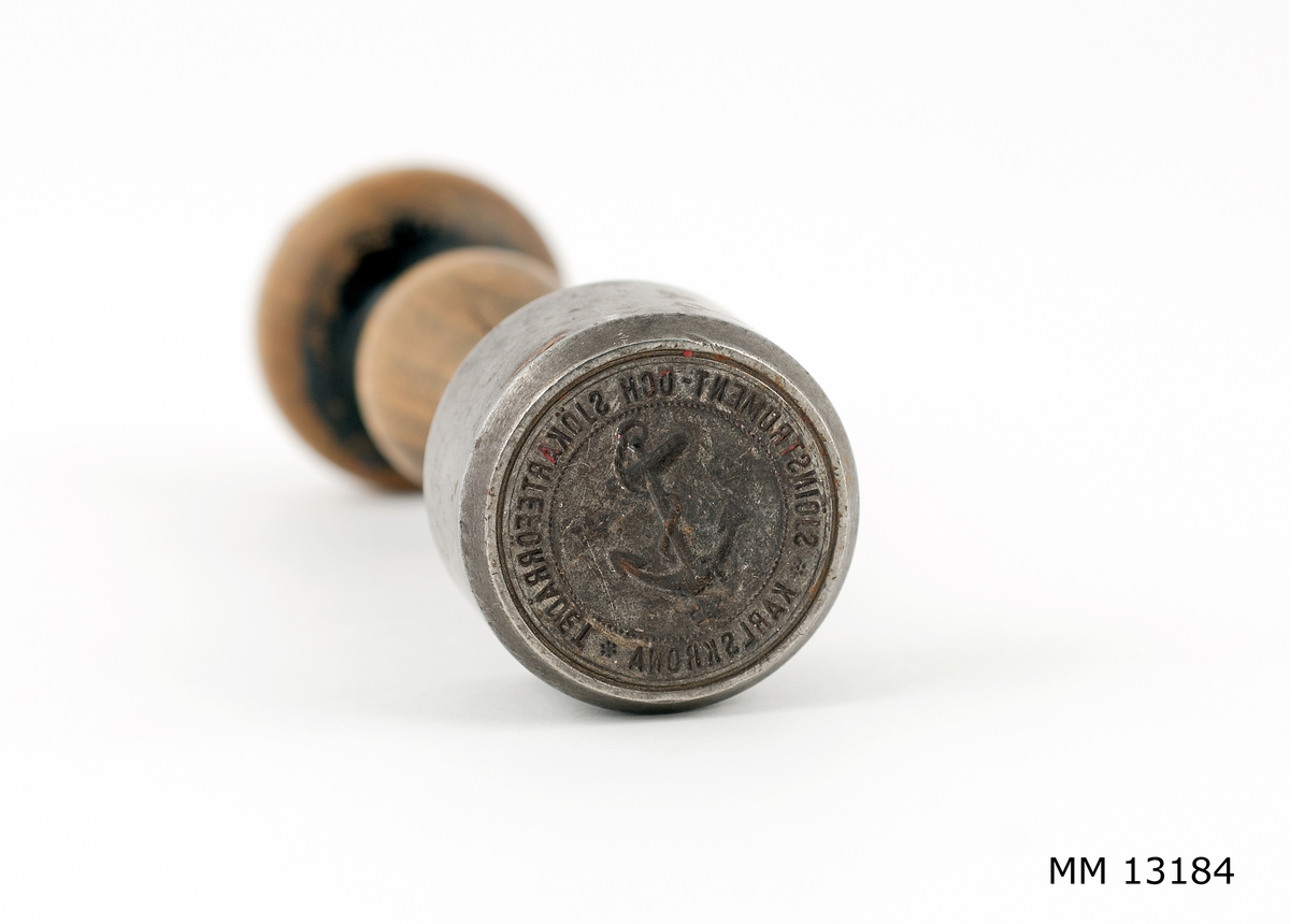 Lacksigill av järn med handtag av trä. Text: Sjöinstrument- och sjökarteförrådet Karlskrona