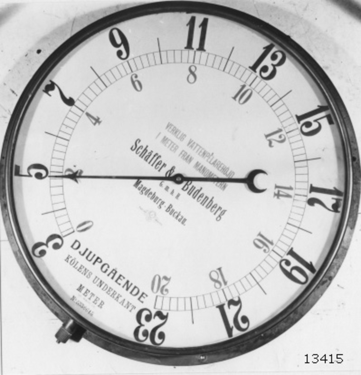 Djupinstrument (manometer) för ubåt. Av mässing och glas. Cylindrisk, med glas över tavlan. Skalan graderad i svart 3-23, i rött 0-20. Märkt: Draken för. Text på tavlan: Verklig vattenpelarehöjd i meter från manometern. Schäffer & Budenberg G.m.b.H. Magdeburg-Buckau. Djupgående. Kölens underkant Meter. Spez. Gewicht 1.01. Nr 5338645. Märkt: Braxen.