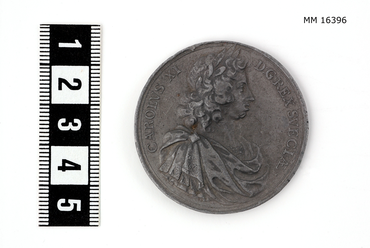 Cylindrisk medalj av tenn. Åtsidan: CAROLVS XI D: G. REX SVECIAE. Bröstbilden, höger sida, lagerkransad, i rika, brämade mantelveck uppfästade över axeln genom ett rutformigt smycke, halsen bar. Nedanför, nästan osynligt: AE. Frånsida: HOC ENSE. LIBERA VIT. En hand ur skyn håller ett svärd, vars fästeknapp och parerstång är prydda med tre kronor (otydliga) och på klingans början vid fästet konung Carl XI namnchiffer (nästan osynligt), över Skånes vapensköld (ett krönt griphuvud). Under skölden 1679. Överst ett strålande JEHOVA (hebreiska).