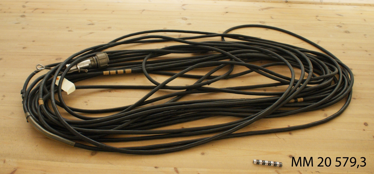 Kabel svart gummi.
L = ca 2000mm  D = 15mm
Försedd med kontakter i båda ändar. Den ena stor dosa i rostfritt med säkringvajer att fästas till hydrofonen. Lagad på flera ställen med isolerband.

Fler delar finns i Berggården