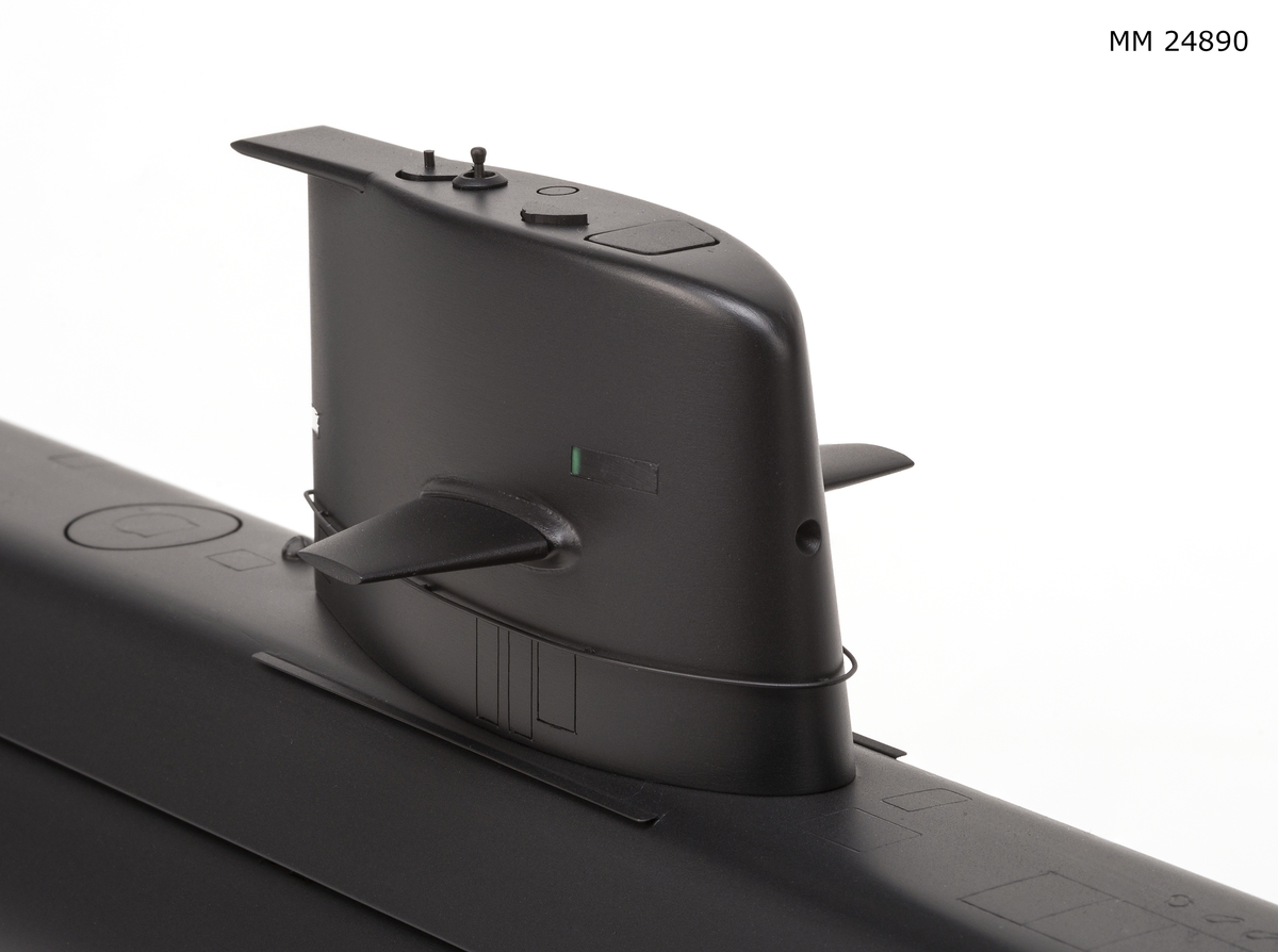 Ubåtsmodell Gotland i monter. Modell av alträ med detaljer av mässing, målad med cellulosafärg. Svart skrov. Monter av plexiglas på träplatta. Mässingsbricka i montern med uppgifter om modellen.