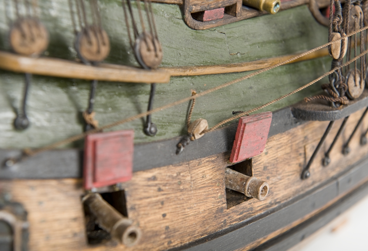 Flöjtskeppsmodell. Riggat med stående och löpande gods, segel av bomull. Bogspröt m. 2 blindor. Fock- o stormast med märs- och undersegel. Latinsegel på mesanmasten. Galjon m. lejon. 2 bogankare, båt på skrå midskeppsöver storluckan. På halvdäck 2 metallkanoner, 4 bogkanoner, samt 4 kanoner på låringen. 1 campagnelykta. Mörkbetsat skrov med 2 svarta berghult, svart bottenfärg. Akterspegel rikt ornerad med 6 fönster. Föremålets form: Helmodell