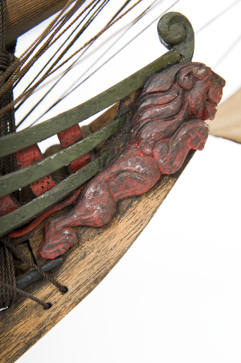 Flöjtskeppsmodell. Riggat med stående och löpande gods, segel av bomull. Bogspröt m. 2 blindor. Fock- o stormast med märs- och undersegel. Latinsegel på mesanmasten. Galjon m. lejon. 2 bogankare, båt på skrå midskeppsöver storluckan. På halvdäck 2 metallkanoner, 4 bogkanoner, samt 4 kanoner på låringen. 1 campagnelykta. Mörkbetsat skrov med 2 svarta berghult, svart bottenfärg. Akterspegel rikt ornerad med 6 fönster. Föremålets form: Helmodell