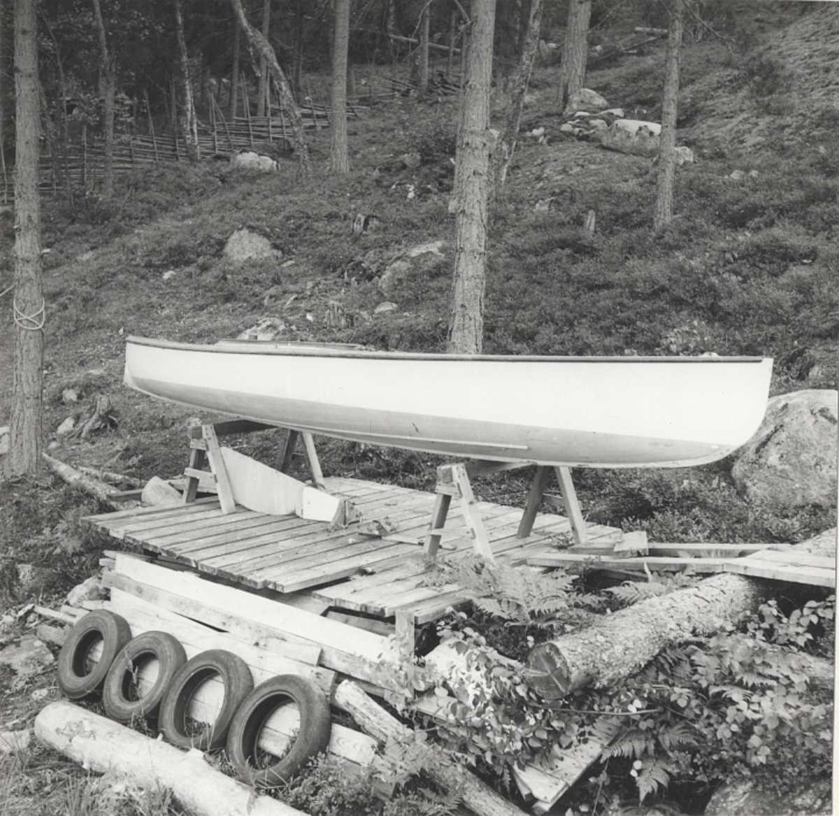 Segelkanot, klass III B, med Güntherrigg och centerbord. Fall, skot och block saknas. Byggd i mahogny, furu och duk. 
Vita fribord och gult däck. Mittfiskar och sarg i mahogny.