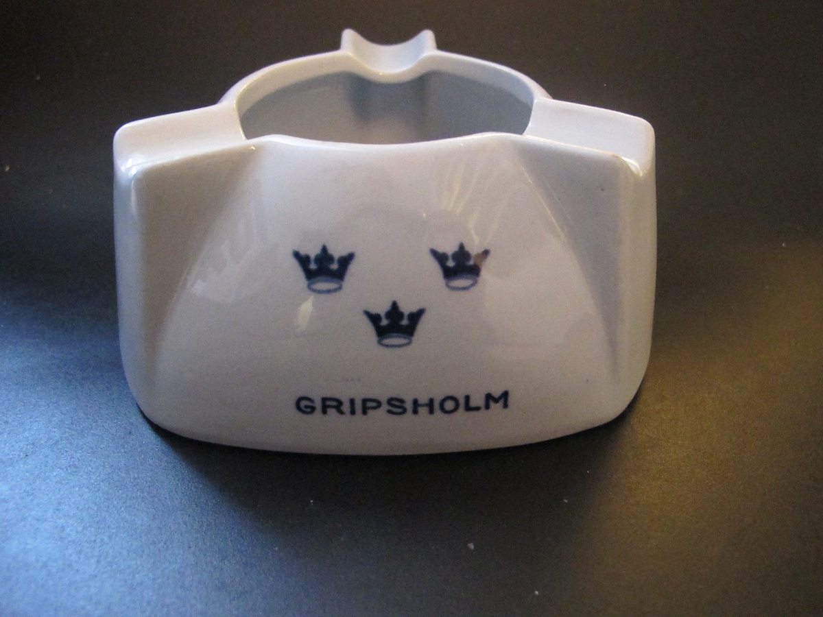 Trekantig i ljusblått porslin med höga, rundad kant avslutat med ett runt hål och tre "cigaretthållare". Text i mörkblått: KUNGSHOLM, GRIPSHOLM, DROTTNINGHOLM med SALs emblem tre kronom över vardera namnet.
Text under botten: SWEDISH AMERICAN LINE GOTHENBURG DIRECT NEW YORK & CANADAFöremålets form: Trekantig