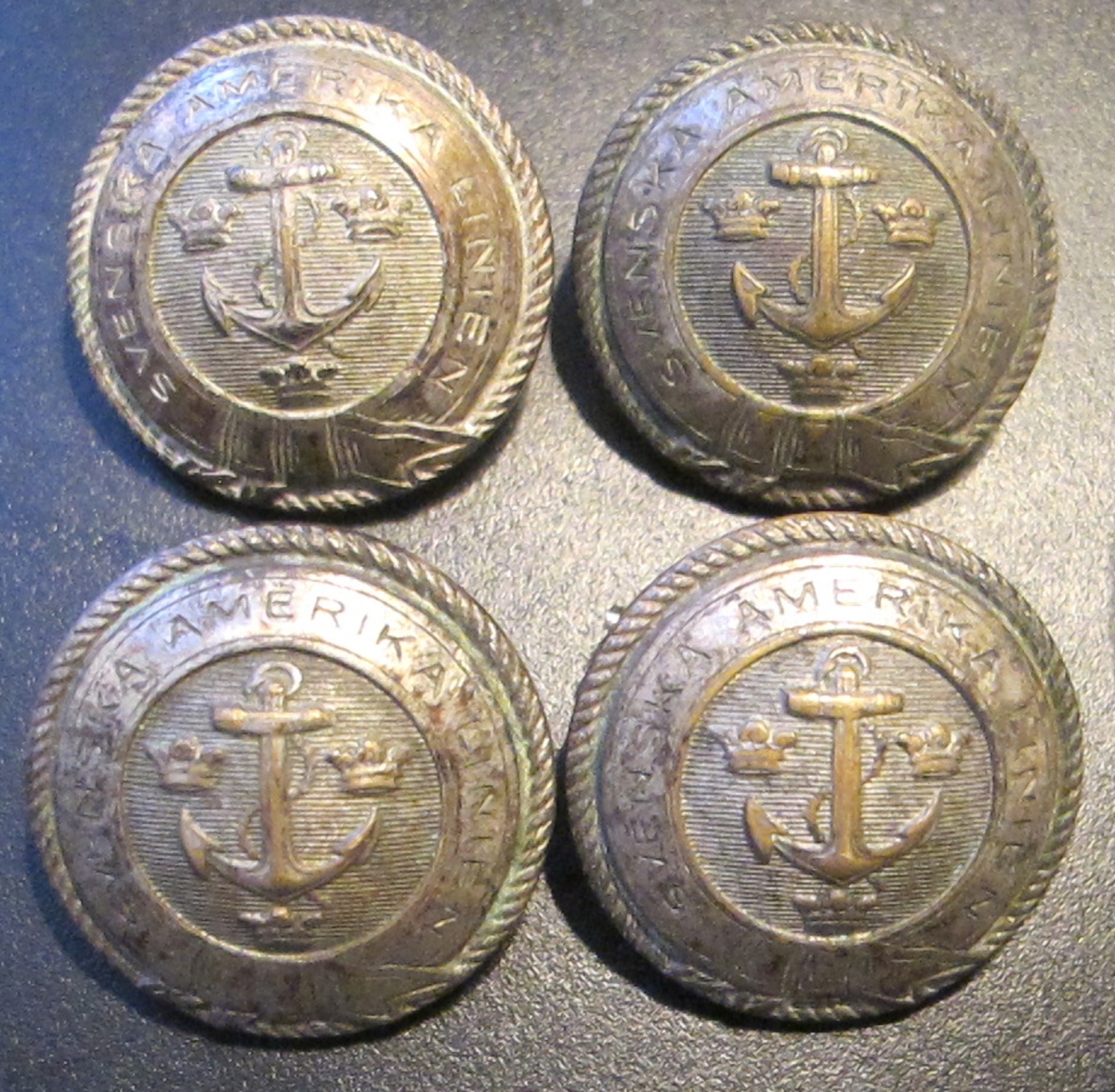 Runda, konvexa, metallknappar med präglat ankare omgivet av SAL:s emblem med tre kronor mot räfflad bakgrund, inramat av en slät bård i form av ett band med texten SVENSKA AMERIKA LINIEN, avslutas mot kanten av en repdekor.

Baksidan pålödd ögla för fästande av knappen på plagg, två hål, texten: C.C. SPORRONG & CO STOCKHOLM.