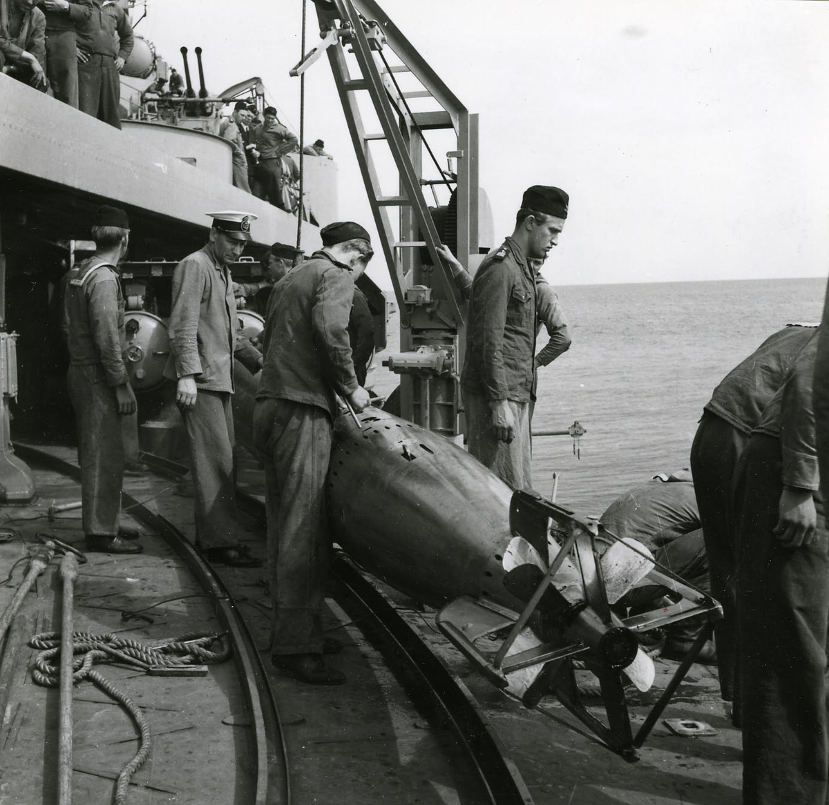 Manskap i arbete med en torped på däck på kryssaren Tre Kronor, 1949.