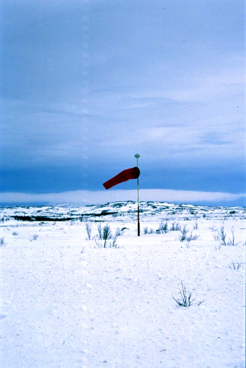 Lufthavn, vindvimpel. Fjell i bakgrunnen.