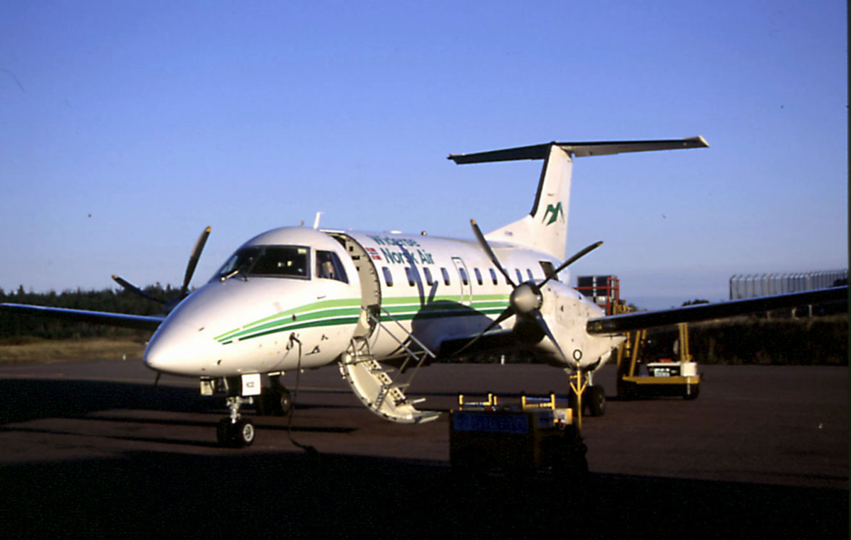 Lufthavn, ett fly på bakken Empresa Brasileira de Aeronautica SA EMB-120RT LN-KOC fra Widerøe Norsk Air. Landgang ved flyet.