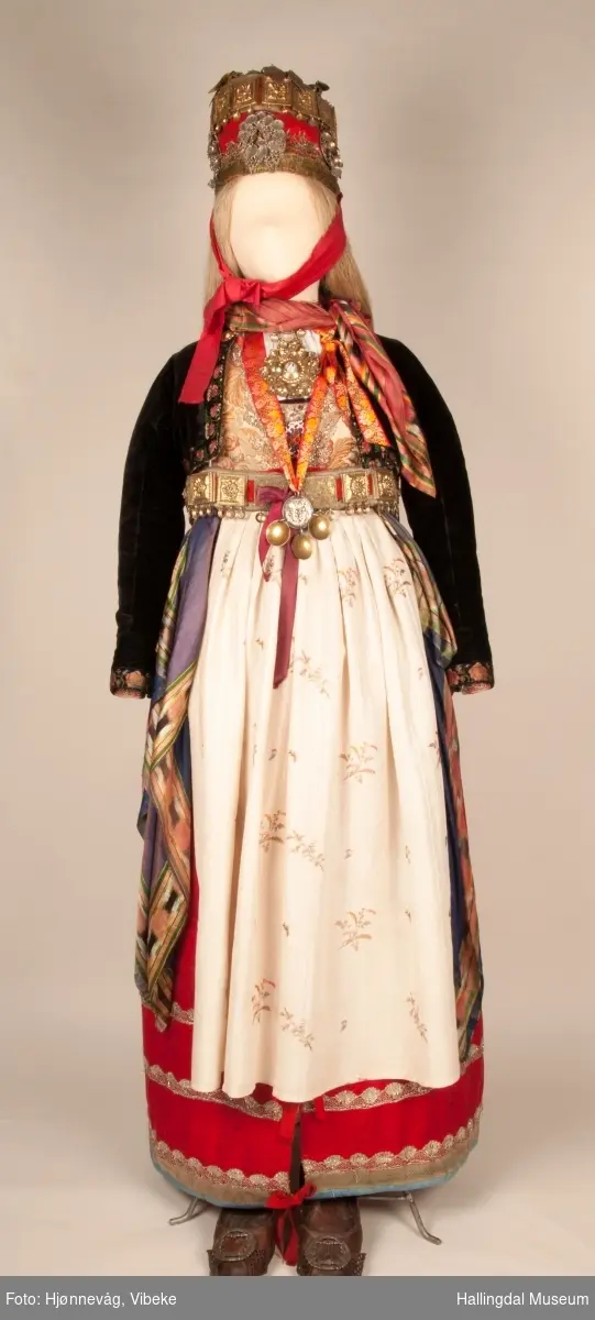 Drakten står utstilt i den faste bunadutstillingen på Hallingdal Museum, Nesbyen.  Den ble satt opp på grunnlag av et bilde fra Norsk Folkemuseum, tatt ang. av Axel Lindahl.  Tidfestet til 1877-78.  Høyde på overdel ble bestemt etter lengden på trøya.  Utelatelsen av det store bryststykket og andre forandringer ble diskutert med Ågot Noss og godkjent.  Ny dokke ble bygd opp med utgangspunkt i stakkens mål.
HFN 03387-stakk med liv.  Stakk og liv ble skilt 5.1.1999, rød ulltråd med tråklesting festet delene sammen, fjernet.  Stakk festet til liv i ny høyde med store attersting med rødt bomullsgarn.  Det ble sydd understakk i ubleket lerret med vattering av dacronvatt, for å få riktig profil.
HFN 03386 Forkle er noe for kort.
HFN ? Skjortering, sydd fast i skjorta.
HFN 00677 sølje, sydd fast i skjorta.
HFN 00533 sølje sydd fast i skjorta.
HFN ? Perleklut, sydd fast i skjorta.
HFN 00560 Angus Dei, påsatt ny silkesnor.
HFN 06695 Silketørkle, blått, festet i forklesnora
HFN 03499 Silketørkle festet i forklesnora
HFN 06694 Silketørkle, rødt rundt halsen
HFN 03603 Brudelue
HFN 03137 Stølebelte, påsatt bendelbånd, disse ligger over skuldrene for å holde beltet oppe.
HFN 03318 Linskjorte.  Vasket: desember 2000
HFN 01815 trøye i svart speilfløyel.