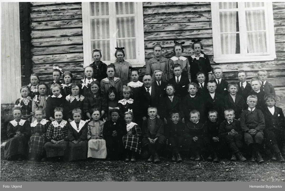 Biletet er teke på Tuv skule i 1922.
Fryste rekke frå venstre: Karoline Berg; Maria Hovde; Karoline Bakke; Sigrid Støyten; Kari O. Ødegård; Anne Purkestad; Margit Fausko; Knut Rusto; Arne O. Tuv; Oskar Vøllo; Embrik Vøllo; Jakob Venås; Ola E. Fekene; Ola O. Tuv.
Andre rekke frå venstre: Ingrid Hovde; Ingebjørg Ødegård,dotter til Karoline,fødd Grøndalen; Margit Venås; Guro Viljugrein; Margit O. Tuv; Elsa, fosterbarn til Erik Anderdal;  Ragna Sletten; Otto Sletten; Olav Sletten; Ola J. Vøllo; Ola A. Anderdal; Trond Brandvoll; Ivar E. Anderdal.
Tredje rekke frå venstre: Ingrid Bakke (nørdre); Kristi Hovde; Barbro Viljugrein; Birgit A. Venås; Ingebjørg A. Anderdal; Karen Sletten; Arne T. Ødegård; John Vøllo; Ola O. Vøllo; Ola Venås (Fausko); Andres Vøllo; Knut K. Berg.
Fjerde rekke frå venstre: Kari Bakke; Margit Bekkevoll; Kari A. Anderdal; Maria K. Berg; Signe Tuv.