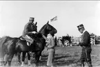 SFK:s vårtävlingar 1934. HKH prins Gustaf Adolf på Rockaway mottager 1.pris (av generalskan Tyra af Edholm). Prinsen medför två hästar till prisutdelningen, vilket betyder att han även tagit ett platspris med sin andra häst Aida.