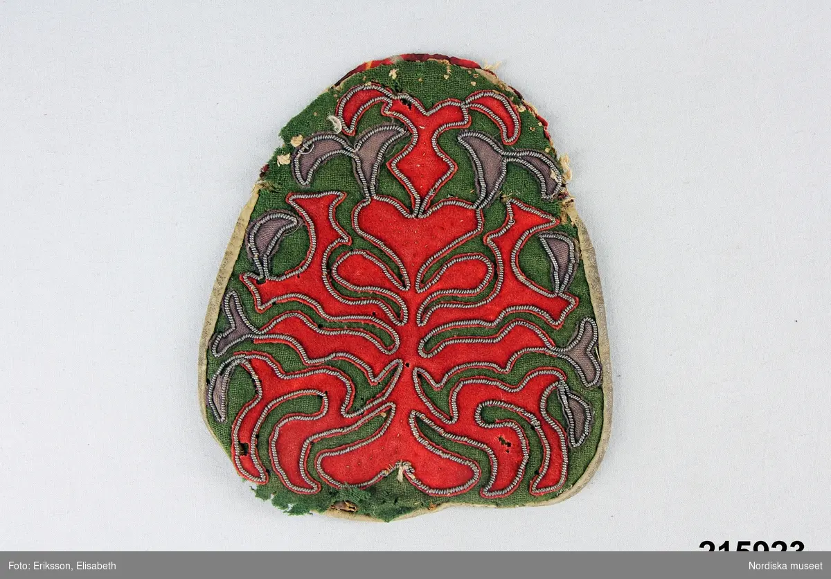 "Kjolsäck, framsida grön vadmal, röda applikationer, tennbroderier; baksida av skinn, bygel fattas."
/enligt intendent Inga Wintzells anteckningar