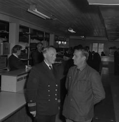 Två män samtalar i persedelförrådet