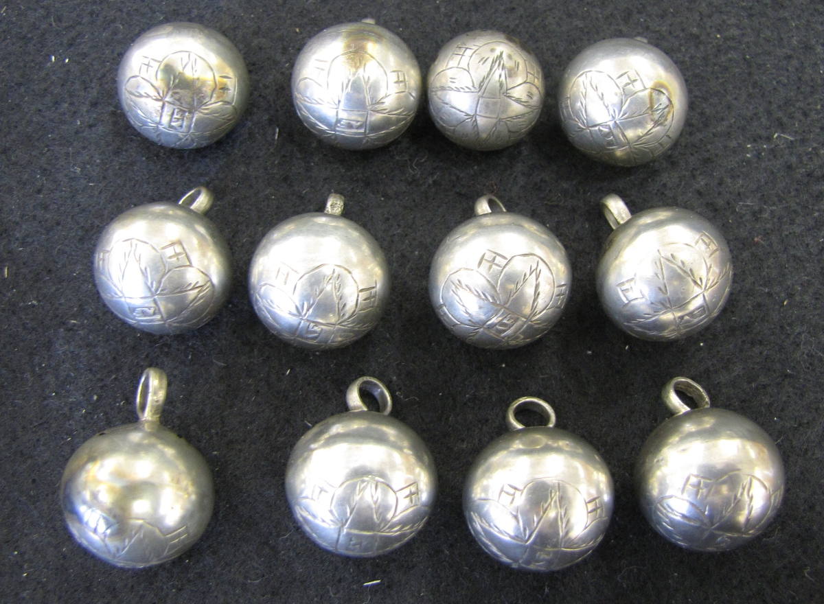 Tolv klotrunda silverknappar med ingraverat blommönster. I blommans mitt är samtliga knappar stämplade ''AF''. Enligt Vänersborgs museums katalog av år 1904-05 är knapparna ''norska bondknappar'' men stämpeln ''AF'' påminner mycket om Anders Falcks stämpel.

Eventuelt är knapparna tillverkade av silversmeden Anders Falck vilken blev mästade i Jönköping 1708 eller 1709. Han blev ålderman omkring 1711 och tjänstgjorde även som rådman. Han avled 1739.