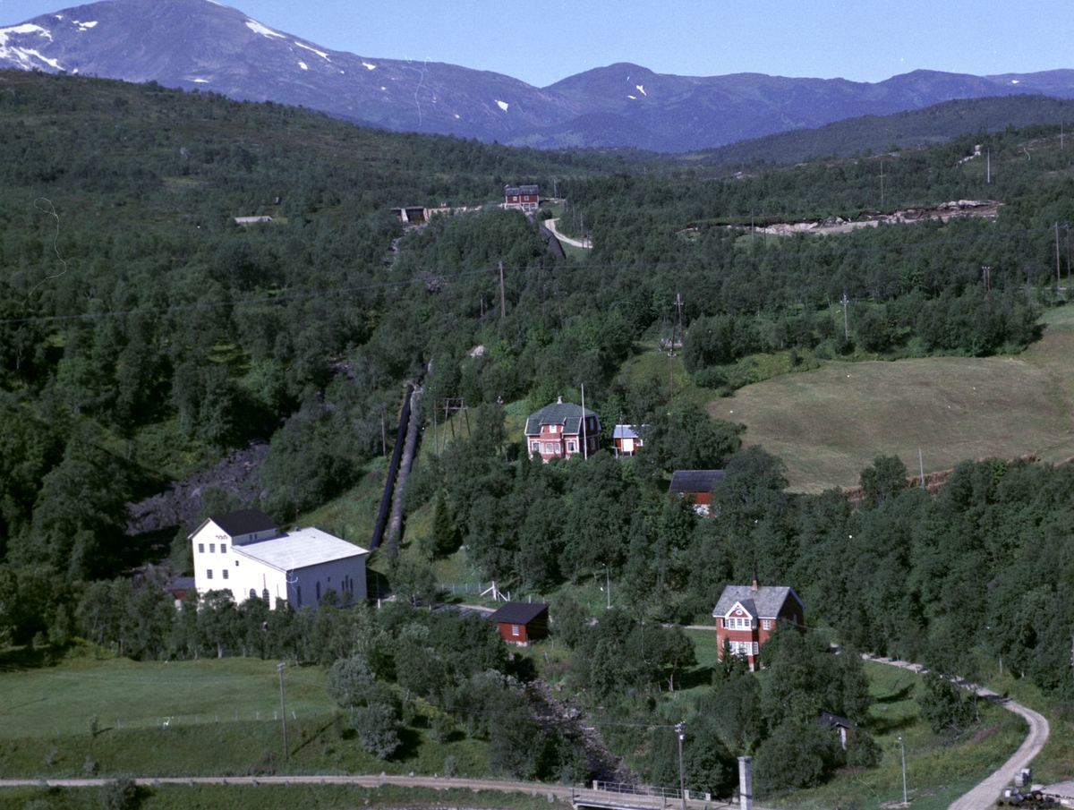 Flyfoto av bebyggelse, rørgate og kraftverk omgitt av skog i Gausvik ...