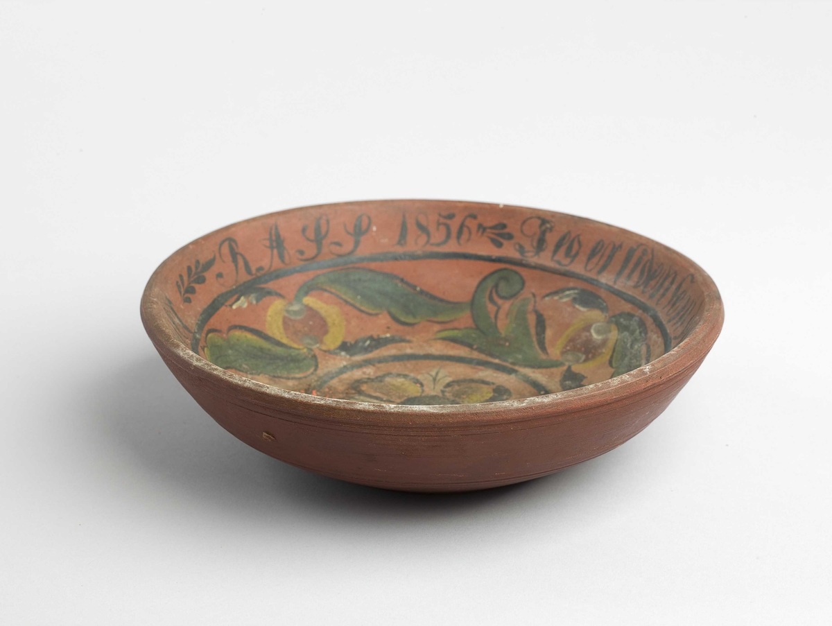 Liten rund ølbolle. Har handmåla dekor på innsida, blomsterliknande mønster.
