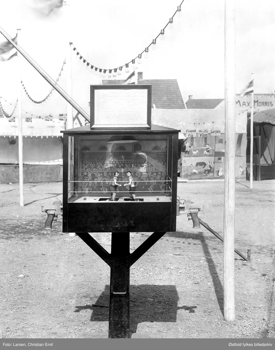 Østfoldutstillingen i Sarpsborg 1930. Boksespill, spillautomat, to bokser-figurer i fornøyelsesavdelingen utendørs (tivoli). Til høyre skimtes inngangspartiet til Max Morris.
Østfold fylkesutstilling i samarbeid med Sarpsborg kommune og Østfold landbruksselskap (100 år) og de andre Østfoldbyene. 
I alt ti avdelinger for skogbruk, landbruk, industri, husflid, osv. Også kulturhistorisk utstilling på Borgarsyssel Museum.