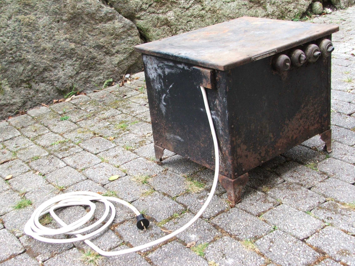 Elektrisk steikjeomn. Dør på eine kortsida med lukkemekanisme øvst. Tjukke veggar. Inni er det to lause steikjeplater. Det er spor til å setje plater på på veggane. Ei plate har kant, den andre ikkje. Øvst på eine langsida er det fire brytarar. Ledning kjem ut på kortsida bak.