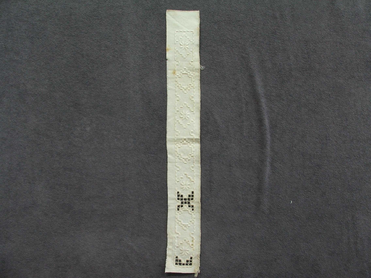 Byrjinga på broderi. Kvitsaum, holsaum. Ein kan sjå korleis holsaumen er gjort.