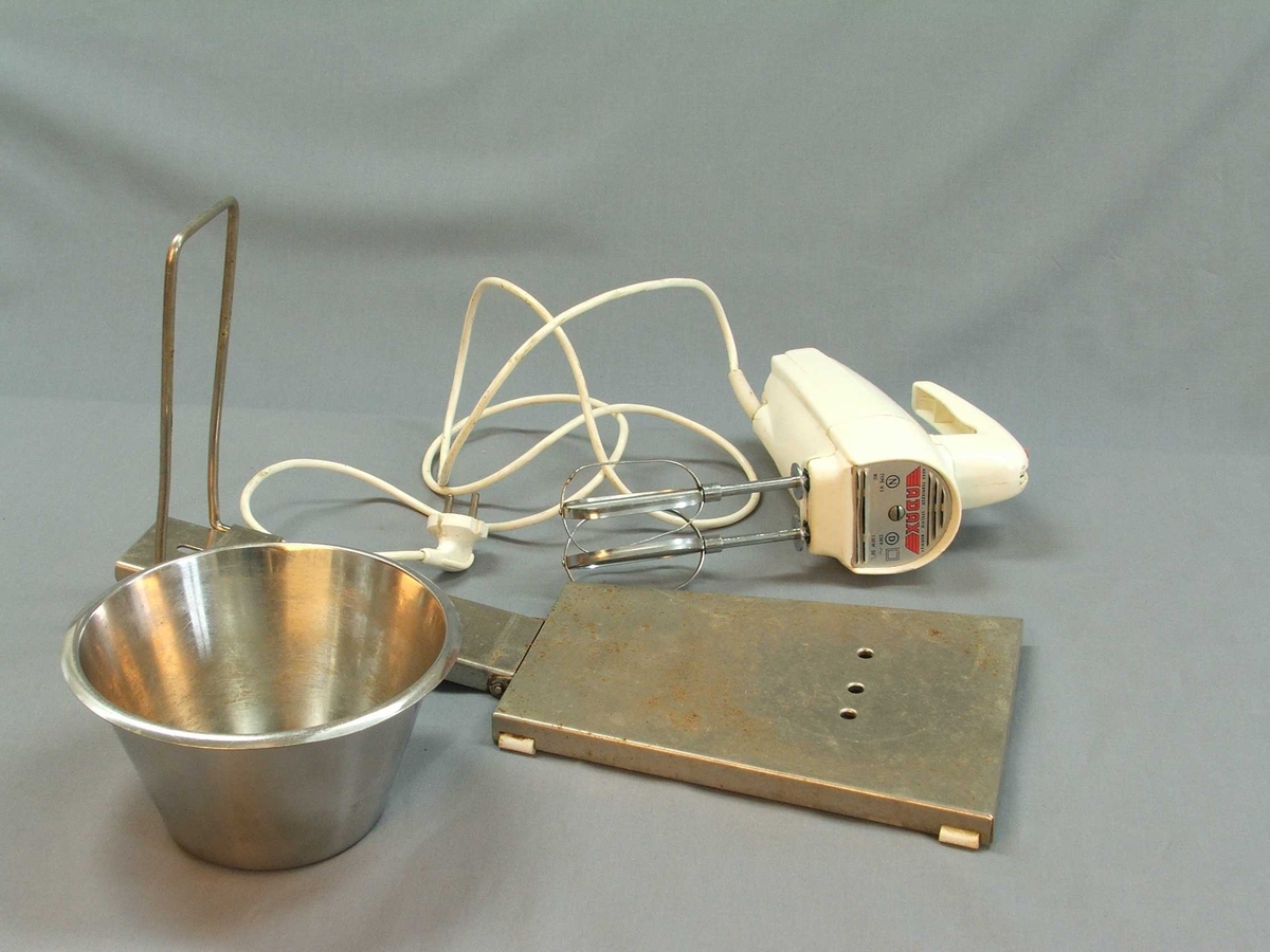 Miksmastar i fem delar: Stativ, bolle, maskin med leidning, to vispar. Stativet er av stål, her kan bollen stå oppå og maskinen stå ned i ei råme med vispane ned i bollen. Bollen er i rustfritt stål. Maskinen er tung, handtak øvst, knapp med fire trinn også øvst. Uttak til vispar under. Vispar samansett av to ovalar med stålband.