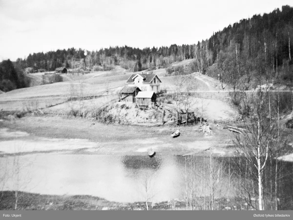 Grytheevja, Ovaskog. Bildet er tatt fra Grythebrua, som ble revet i 1939. Huset tilhørte Marius Lunde F.1889, far til eier av bildet, Mina.

Gunnar Kullerud skriver i 2013: 
Bildet kan ikke være tatt fra Grytebrua, den lå 70-80 m lenger inne i Gryteevja. Vi kan se at bildet er tatt fra land og det er helt sikkert at fotografen har stått på plassen Fauli, tilhørende gården Kongsrud i Ovaskog i Varteig. Det hvite huset heter fra gammelt av Betania.
