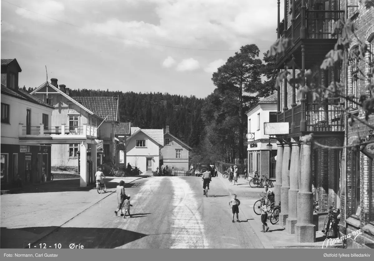 Utsnitt av Storgaten i Ørje i Marker  tatt en gang mellom 1940 og 1950.
Folk går på fortauet og krysser gaten.