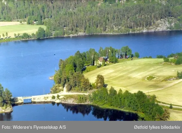 Skråfoto av villa i Sundsberg i Rakkestad 11. juni 1966.
Daværende eier var Alf Greaker?
Bildet viser Sundsbrua på FV655 (Sandbekkveien) i Degernes, Rakkestad. I forgrunnen ser vi Skjeklesjøen og i bakgrunnen er Greåkersjøen.