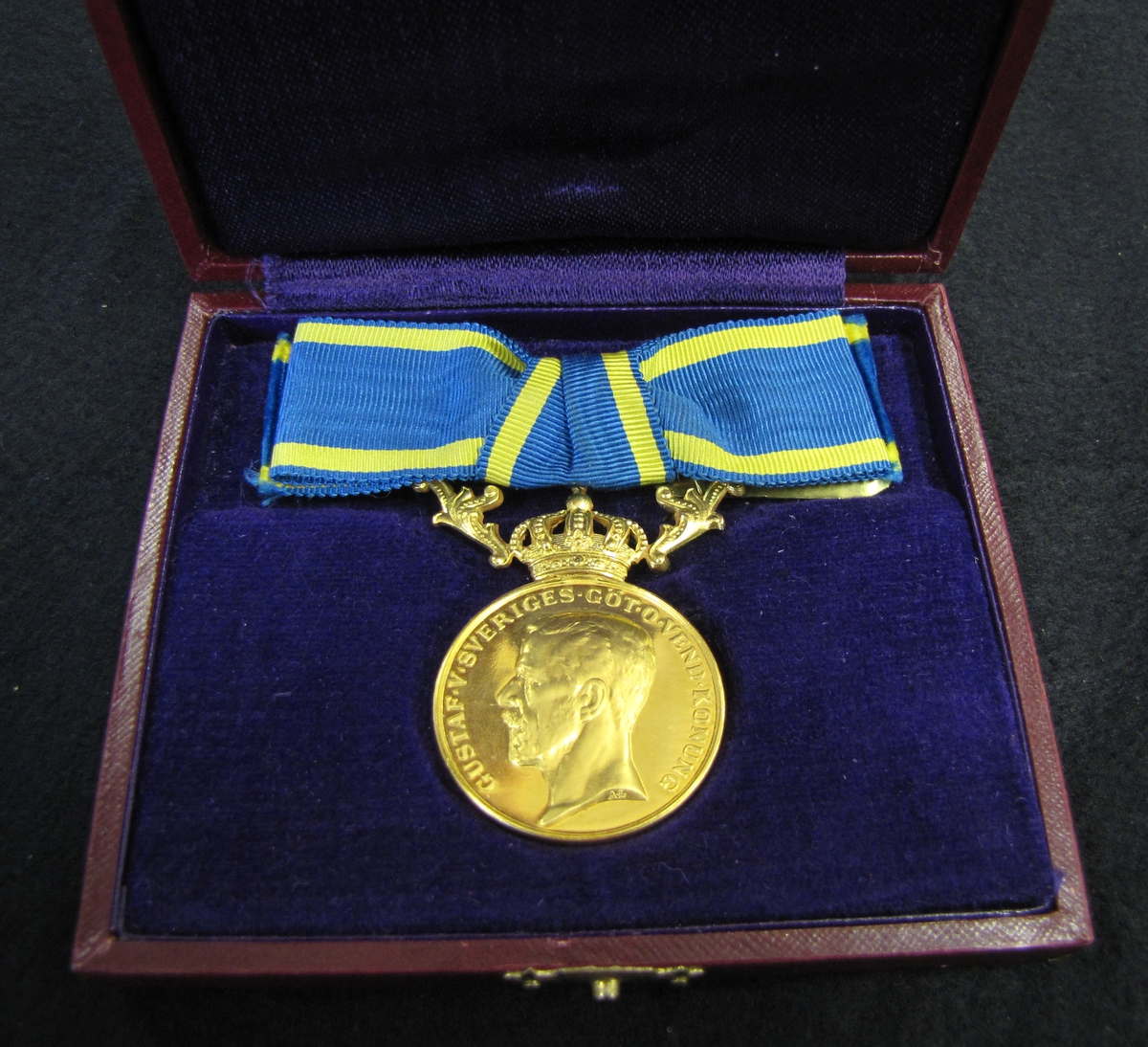 Medalj till Emmy Helena Anna Helander för nit och redlighet i rikets tjänst.  Finns ett etui till medaljen (VM09633:c). 

Medaljen är av 23 K guld försedd med krona och bärornament av 18 K guld.