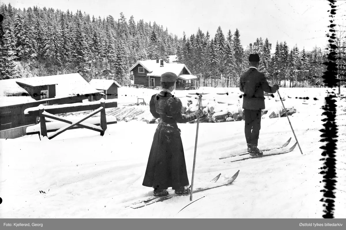 To skiløpere passerer ukjent gårdsbruk. Ukjent sted. Kanskje Nordmarka?