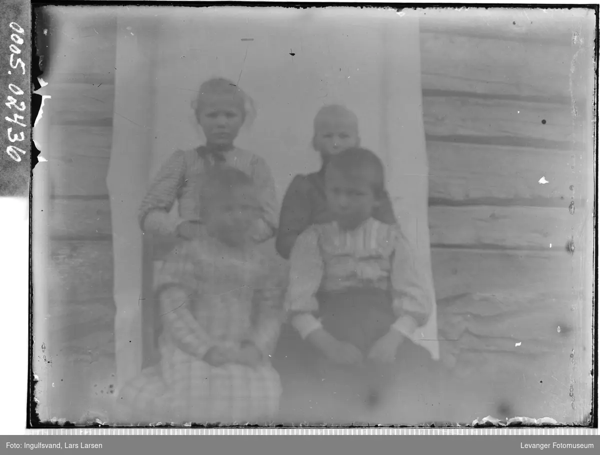 Portrett av fire barn foran et inngangsparti.